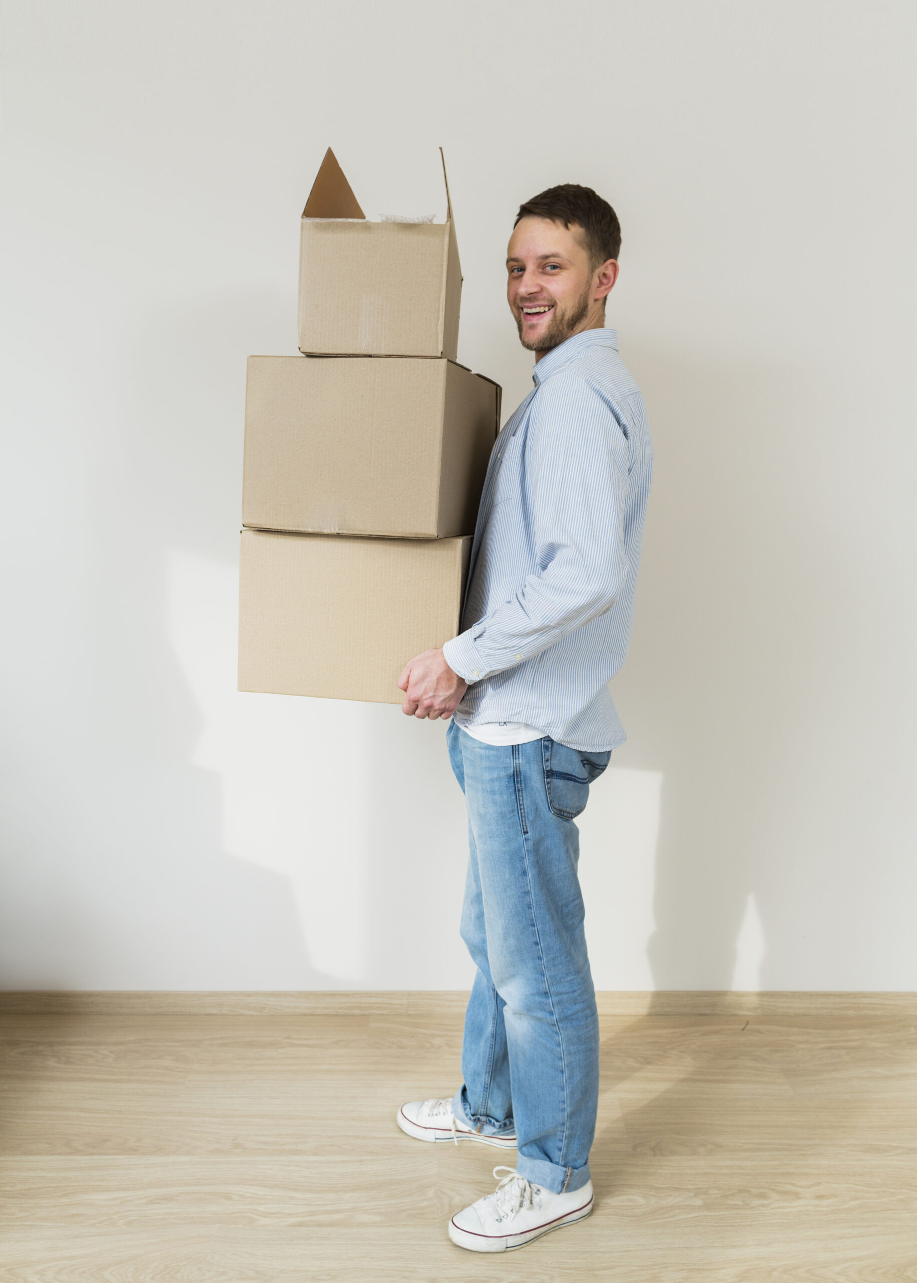 smiling-young-man-holding-stack-cardboard-boxes-hands-his-new-home